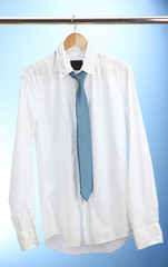 shirt with tie on wooden hanger on blue background