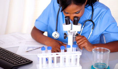 Afro-american nurse woman using a microscope