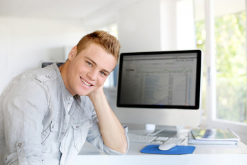 Portrait of young man sitting in front of computer