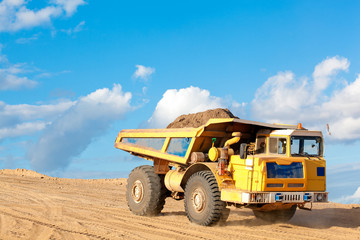 Dump truck with sand or soil in a body at a construction site