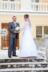 Fototapeta premium Bride and groom at winter season standing on stairs