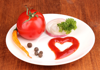 Ripe tomato and spices on plate on wooden table