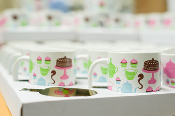 White tea cups with fun cakes pattern in boxes in supermarket