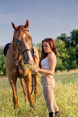 Young girl and horse on a summer meadow on a sunset