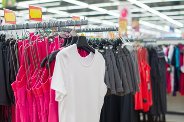 Bright t-shirts and shorts on stands in supermarket