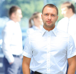 Fototapeta premium Handsome happy business man with colleagues at the back