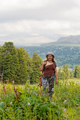 Female hiker with backpack in grass at mountains