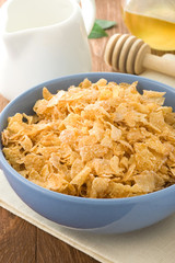 Bowl of corn flakes and milk on wood