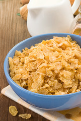 Bowl of corn flakes and milk on wood