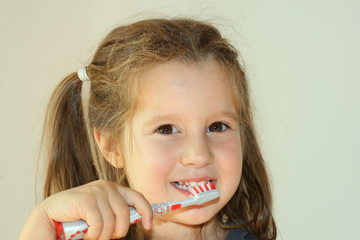 smiling girl washing her white teeth using a toothbrush an