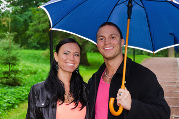 Portrait of young couple under umbrella in the park