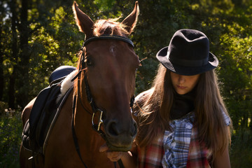 Fototapeta premium Cowgirl in hat with bay horse