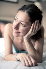 Portrait of a sensual woman lying on bed in hotel room.