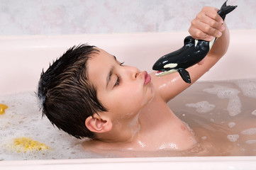 Cute child playing with his toy while bathing