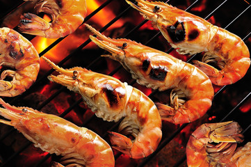 Grilled prawns on flaming grill.