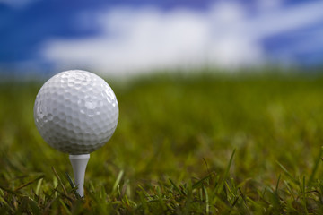 Golf ball on green grass over a blue sky 