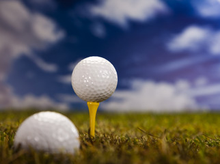 Golf ball on green grass over a blue sky 