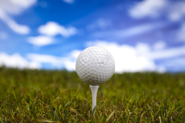 Golf ball on green grass over a blue sky 