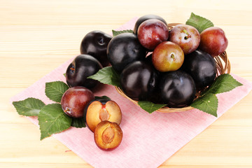 Rip plums on basket on wooden table