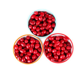 fresh cornel berries in colorful bowls isolated on white