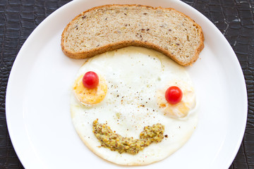 Smiley face from fried eggs with cherry tomatoes