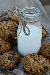 Oatmeal cookies and bottle of milk on canvas background