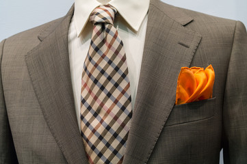 Light grey checkered jacket with brown checkered tie and orange