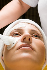 Cosmetician applying facial mask to the face of a woman