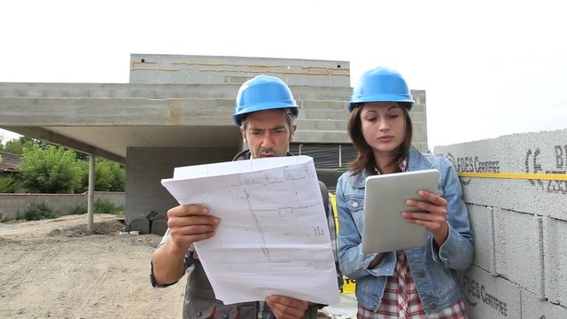 Engineers reading plan on building site
