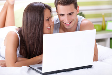 Couple enjoying using laptop in bed