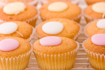 Baked cupcakes with sweet fondant topping on a cooling rack.