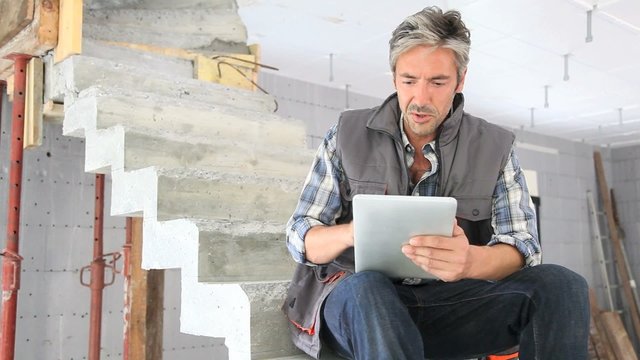 Entrepeneur in staircase under construction unsing tablet