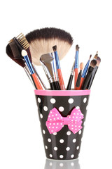 Makeup brushes in a black polka-dot cup isolated on white