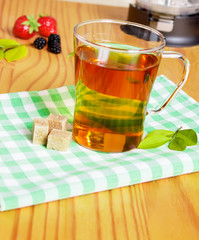 Cup of tea with berry and fruits on old wooden table