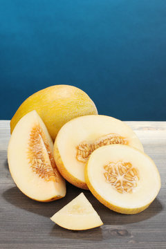 Cut ripe melons on wooden table on blue background