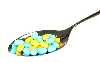 colorful pills on spoon on white background close-up