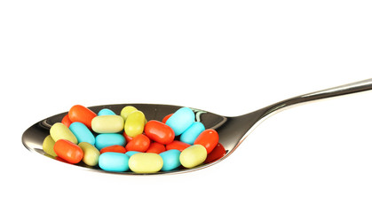 colorful pills on spoon on white background close-up