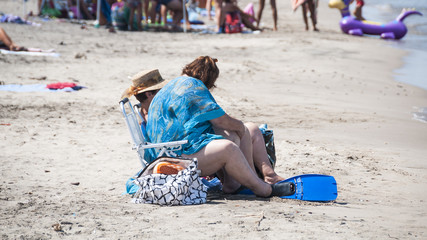 fat woman sitting on the beach at the sea