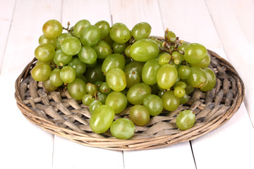 Ripe green grapes close-up on wicker cradle on wooden table