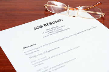 Closeup of resume with glasses on wooden table