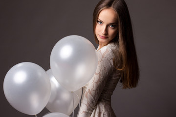Fototapeta na wymiar Beautiful fashion woman in studio with white balloons
