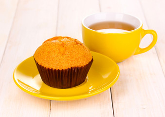 Fresh muffin with tea on wooden background