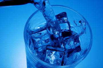 Pouring water into glass full of ice