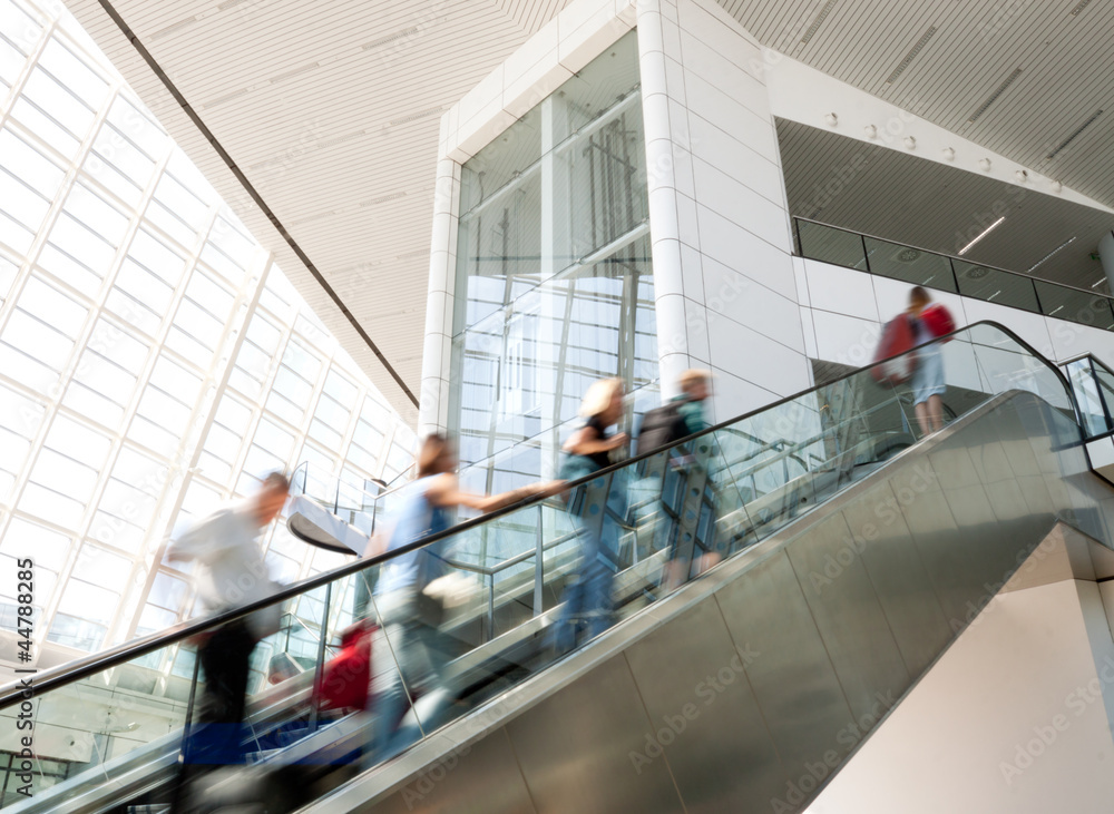 Wall mural Blurred people moving up the escalator