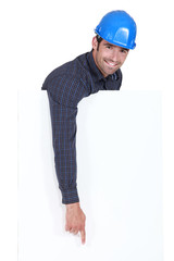Manual worker pointing downwards at poster
