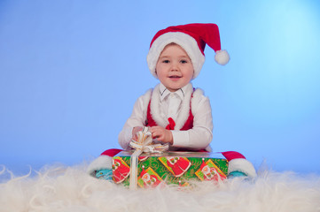 Funny  laughing  baby in Santa suit with a present box