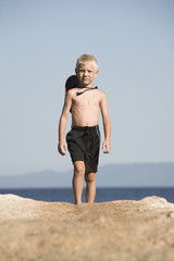 Little boy walks in black short, next to the sea