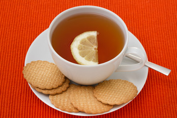 a cup of tea with lemon and cookies