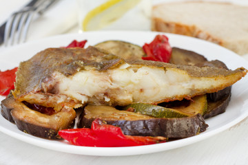 fried fish with vegetables on the white plate
