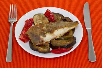 fried fish with vegetables on the white plate
